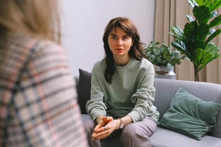A woman sitting on a sofa, talking with a support worker